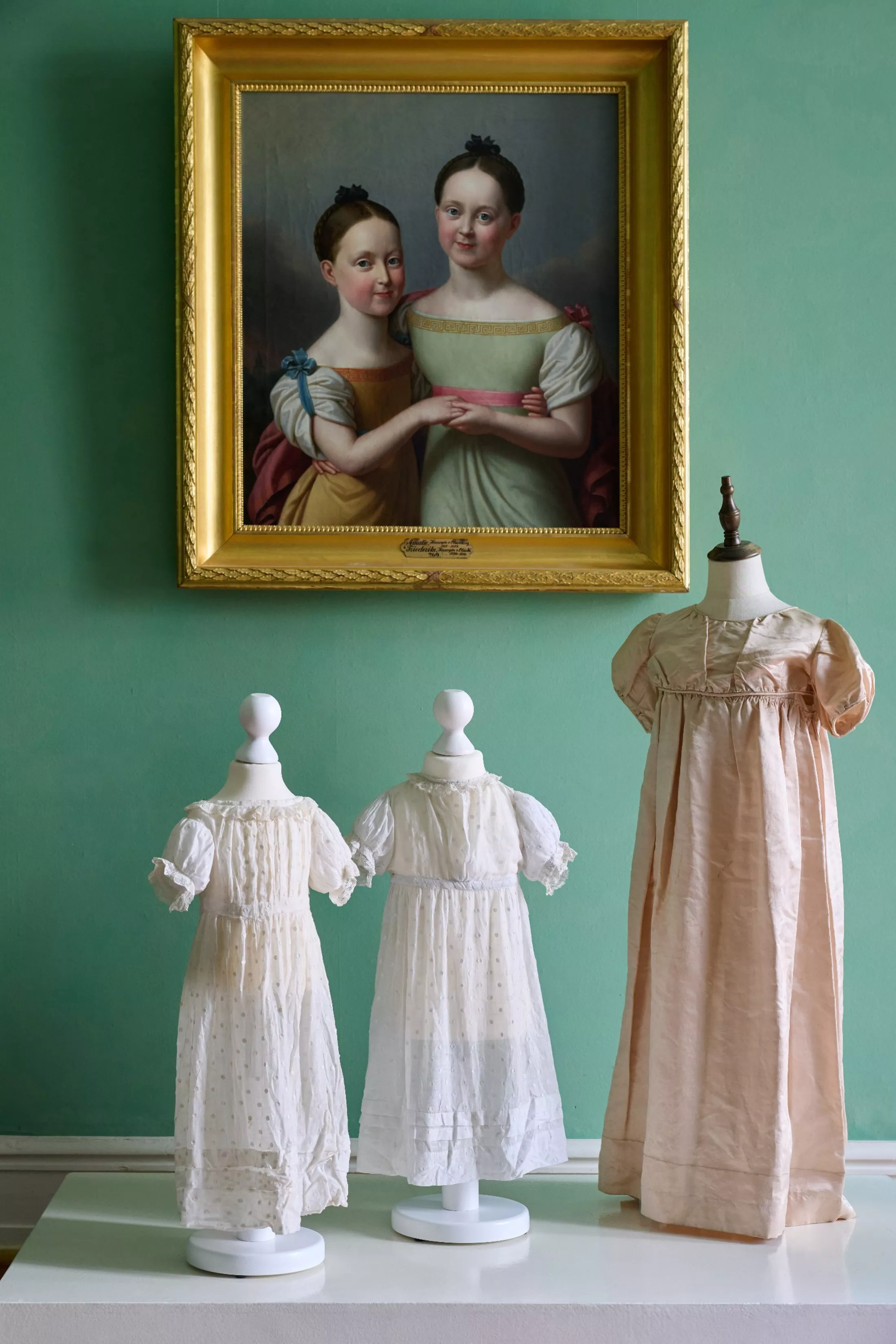 Mädchenkleider, um 1800, weißer, gepunkteter Musselin und Kinderkleid, um 1800, altrosa Seide. Mädchenkleider, um 1800, weißer, gepunkteter Musselin und Kinderkleid, um 1800, altrosa Seide.